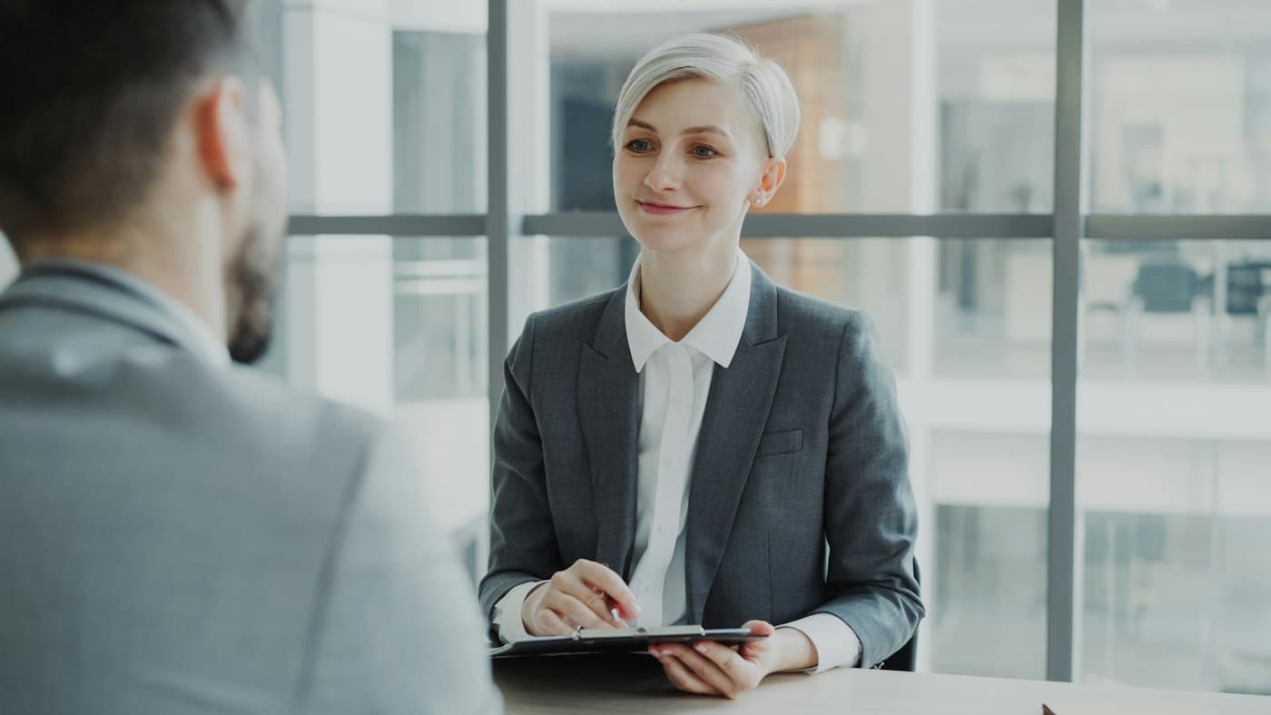 A recruiter and a candidate talking across a desk in a bright office.